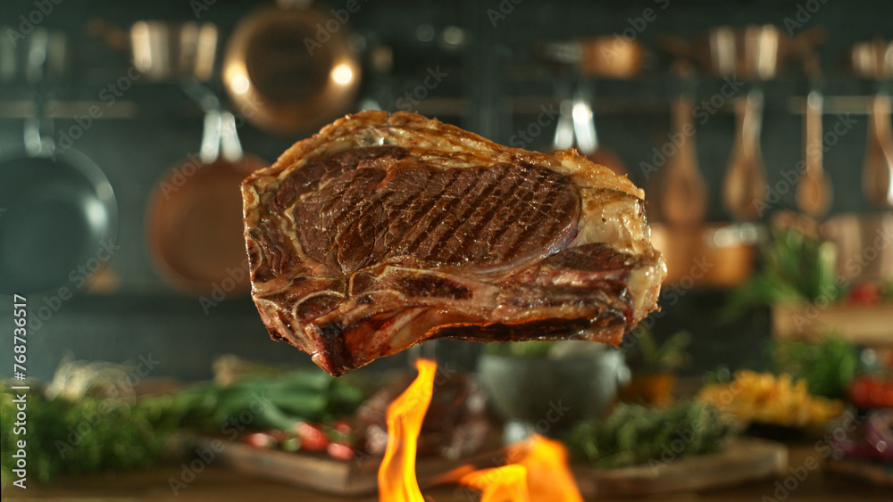 Fototapeta premium Close-up of tasty beef steak flying above cast-iron grate with fire flames