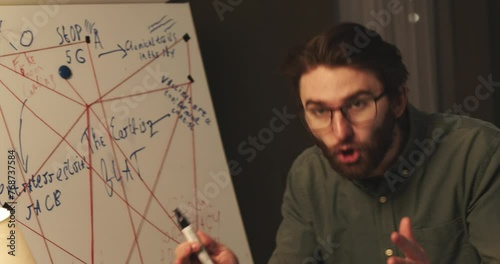 A man emotionally explains a conspiracy theory using a flipchart with a diagram.
