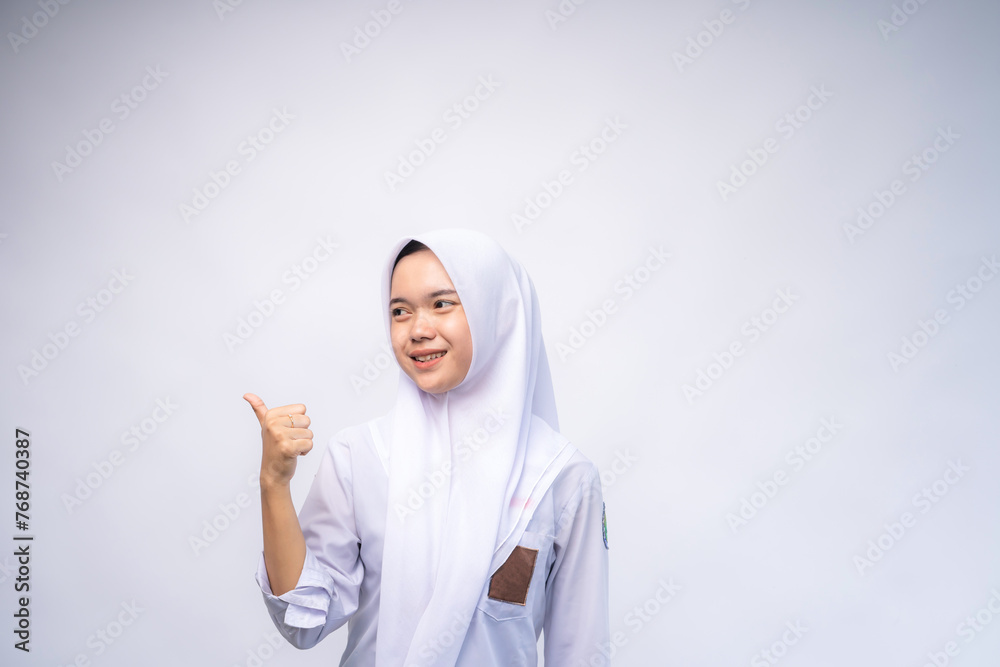 portrait of Indonesian high school student in white and grey uniform giving thumbs up at Copy Space Advertising Your Text. Education concept portrait of Indonesian high school student in white and grey uniform giving thumbs up at Copy Space Advertising Your Text. Education concept