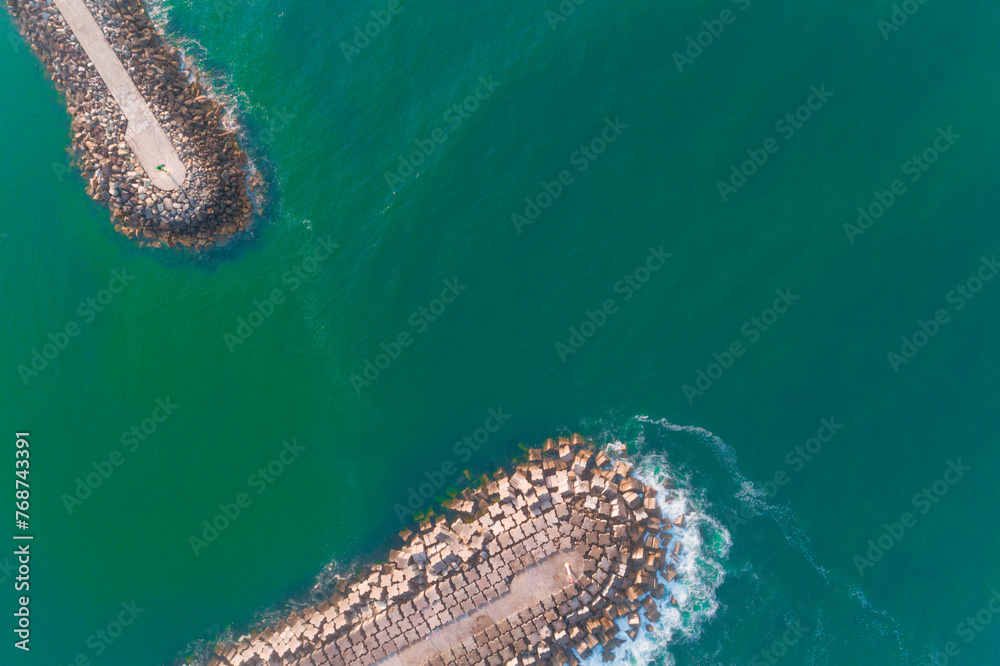 Obraz premium aerial top view of the breakwaters at the entrance of a harbor