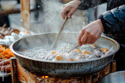 Chef skillfully fries eggs and sausages in a bubbly, sizzling large skillet over an open flame