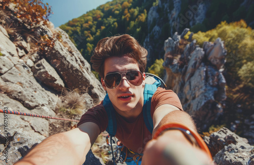 climber with sunglasses taking selfie while climbing mountain, helping friend on rope and reaching out hand to camera, outdoor sport concept
