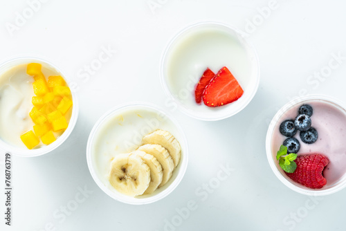 assortment of different yogurts with berries, fruits, mango and banana on white. healthy breakfast