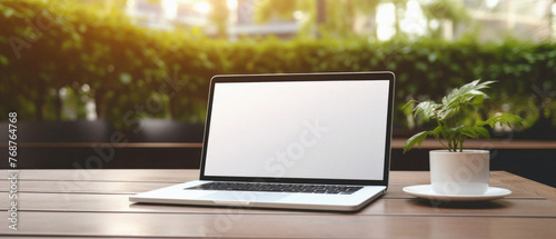 Laptop computer with blank screen on wooden table in coffee shop .