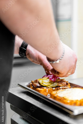 A chef meticulously garnishes a gourmet dish in a professional kitchen, showcasing culinary finesse. The roasted creation features crispy edges, adorned with fresh sliced vegetables