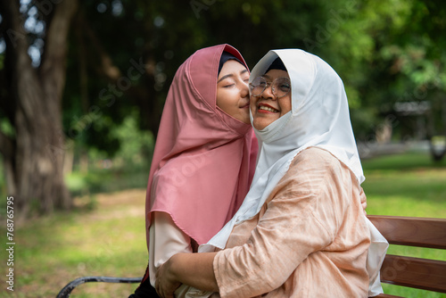 Muslim careful caregiver or nurse taking care of the patient in the hospital park. Happy Muslim mother in hijab hugging daughter. Concept of Savings and Senior Health Insurance, a Happy Family