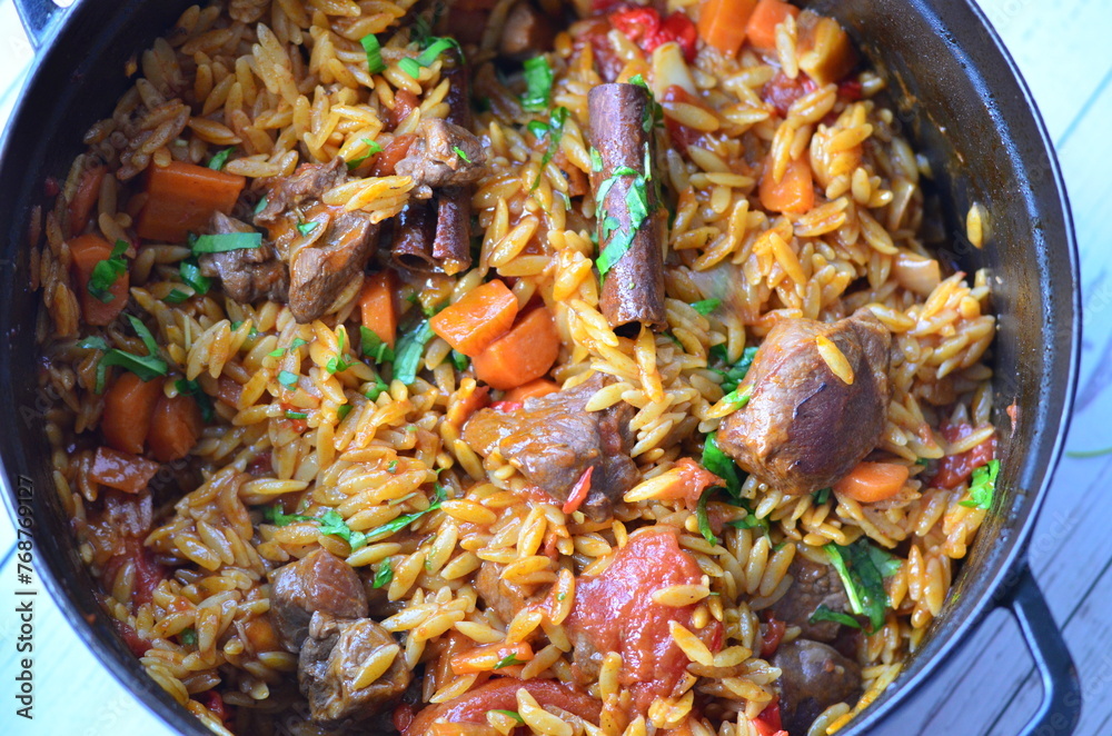 Rice with lamb meat and vegetables on a plate on a wooden table