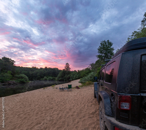 Black SUV on a sandy beach by the river