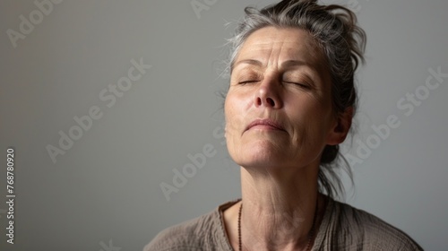 Woman with closed eyes deep in thought or meditation against a neutral background.