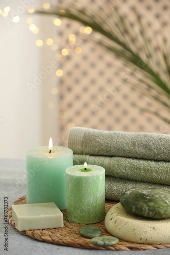 Spa composition. Burning candles, stones, soap and towels on grey table