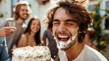Joyful man with cake smeared on his face laughing heartily at a celebration with friends.