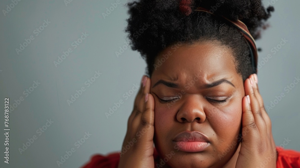 A woman with curly hair wearing a headband pressing her hands against her temples with a concerned or stressed expression. A woman with curly hair wearing a headband pressing her hands against her temples with a concerned or stressed expression.