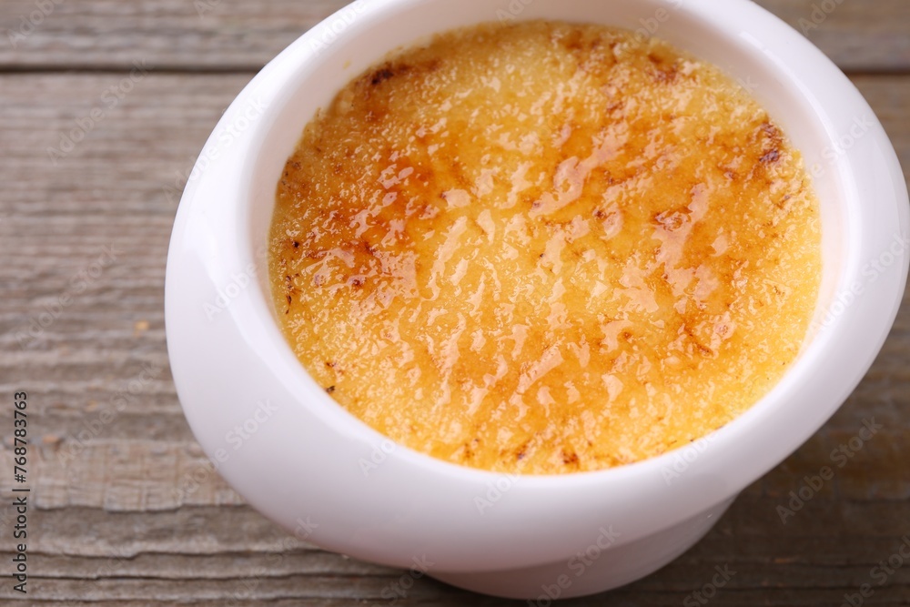 Delicious creme brulee in bowl on wooden table, closeup Delicious creme brulee in bowl on wooden table, closeup