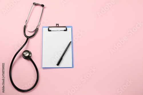 Endocrinology. Stethoscope, clipboard and pen on pink background, top view. Space for text