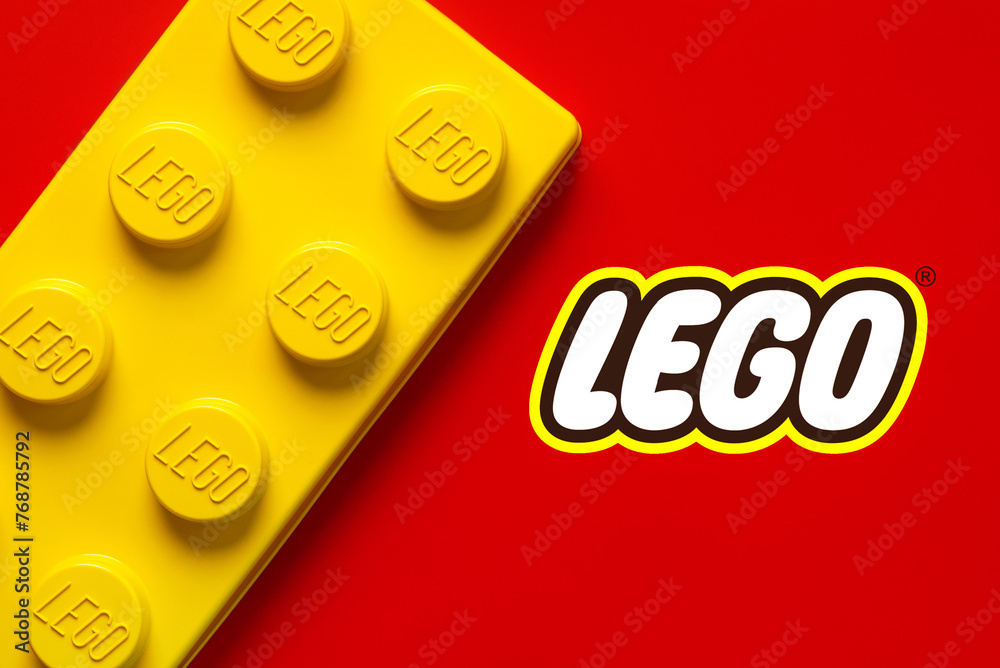 Naklejka premium Close up of large yellow lego block with the Lego logo. Illustrative editorial