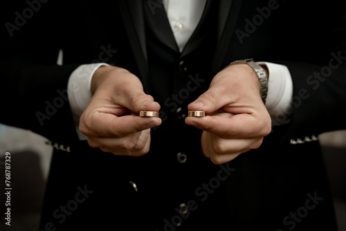 The groom holding the wedding rings in his hand	 photo