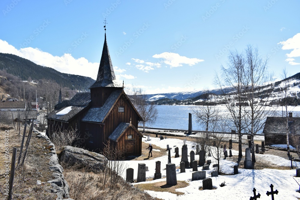 Old Hol Gamle Kyrkje church building stands in the countryside, near a winding road
