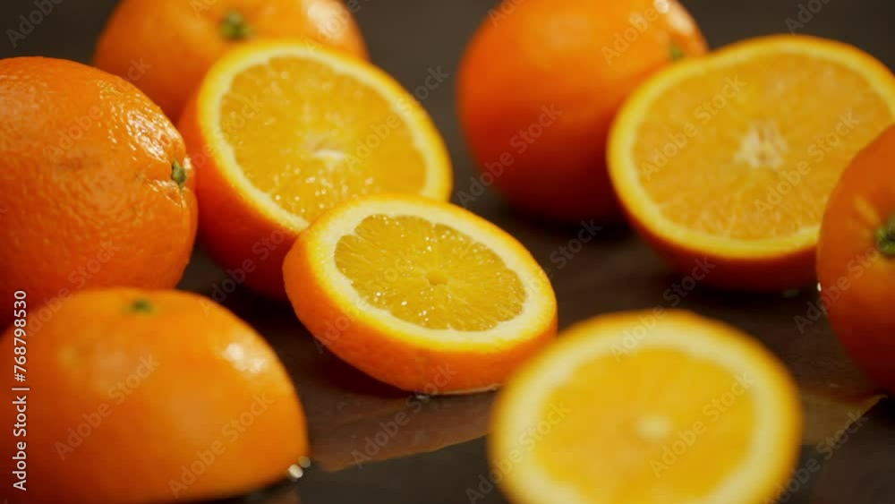 Half of an orange and a piece fall on the table and lie nicely. On a dark background, they are surrounded by whole and pieces of citrus fruits. High quality FullHD footage Half of an orange and a piece fall on the table and lie nicely. On a dark background, they are surrounded by whole and pieces of citrus fruits. High quality FullHD footage