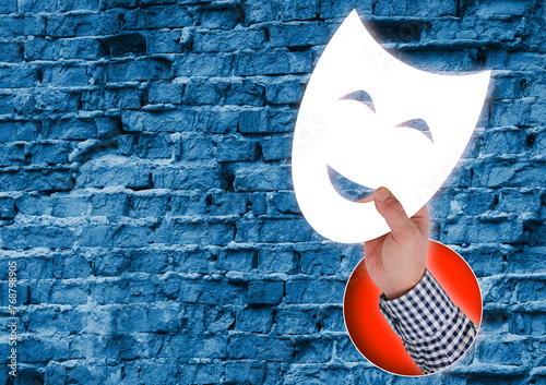 Mystery Behind the Mask. Composite Collage. Hand Holding White Smiling Theater Mask Against Rough Brick Wall Background photo