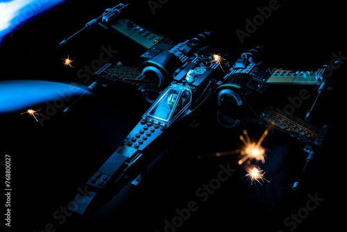 Fototapeta starfighter illuminated in a dark environment, with a bright light shining aroun