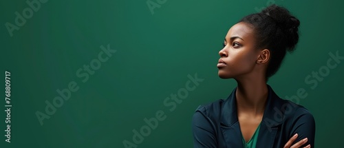 A woman with a determined jawline and raised chin, standing firm against a verdant green background, conveys righteous anger, fighting for what's right, or refusing to back down. Copy space. photo