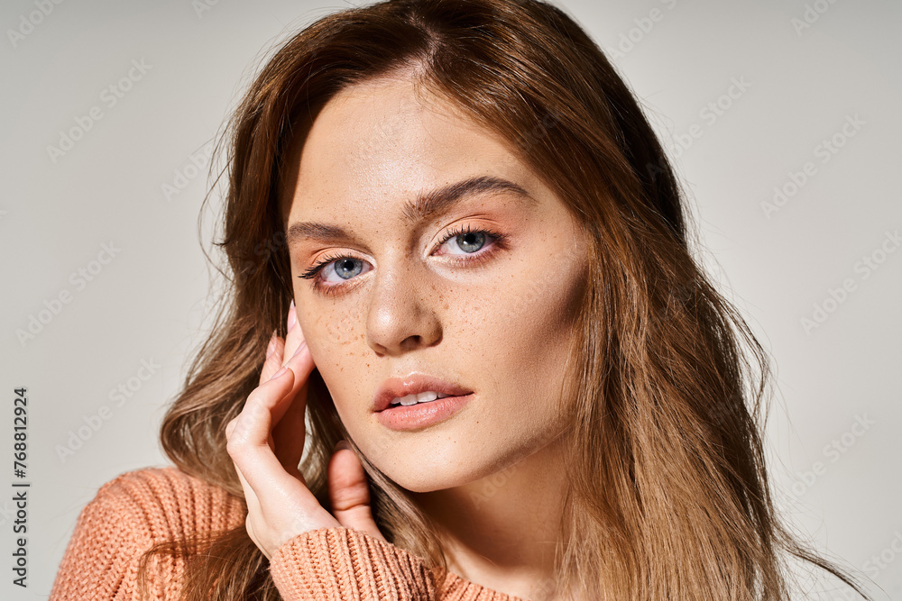 Portrait of pretty woman looking at camera with natural makeup, wearing sweater, touching her face Portrait of pretty woman looking at camera with natural makeup, wearing sweater, touching her face