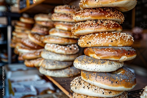 bagels stacked on a bakery shelf, various seeds on top