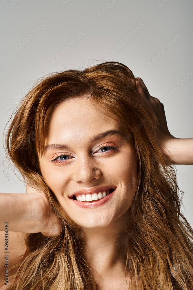 Beauty portrait of smiling woman with natural makeup, looking at camera touching her hair Beauty portrait of smiling woman with natural makeup, looking at camera touching her hair