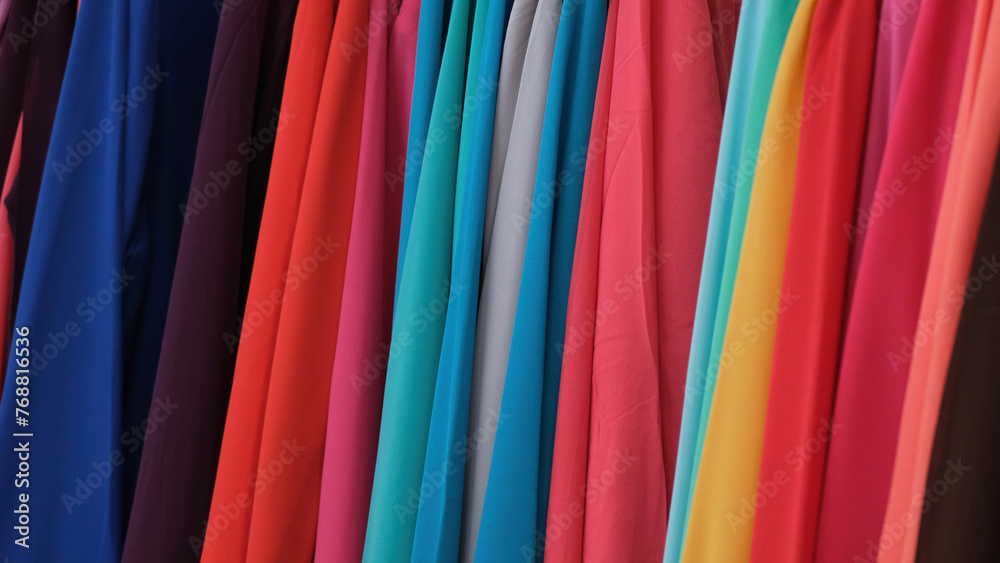 A row of colorful clothing hangs on a rack A row of colorful clothing hangs on a rack