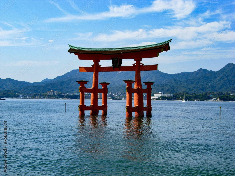 Traditional Japanese torii gate floating in a tranquil body of water in Itsukushima. Traditional Japanese torii gate floating in a tranquil body of water in Itsukushima.
