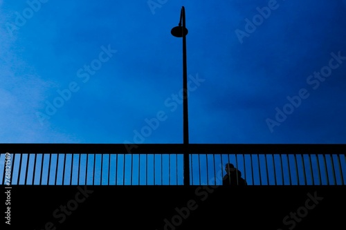 a person sitting on the side of a bridge at night