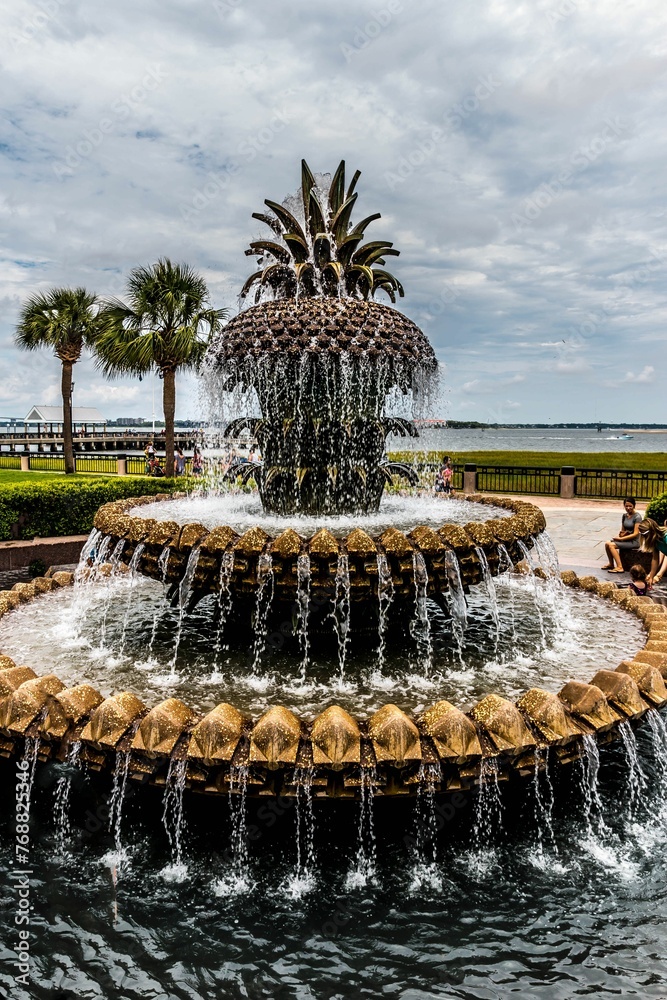 Fototapeta premium Serene fountain rests in the center of a verdant park, with towering palms encircling the area