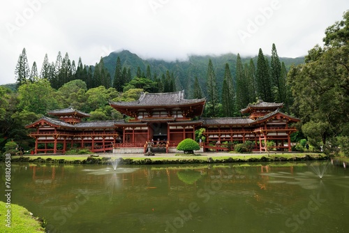 Scenic view of an Asian-style traditional building in a green forest with a pond