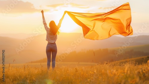 Woman celebrating freedom with an orange cloth at sunset