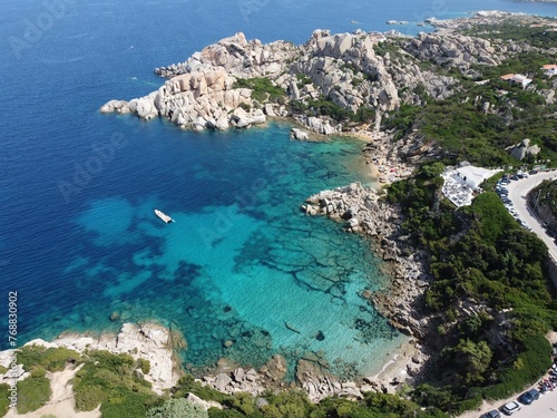 Picturesque beach with a line of boats moored at the water's edge in Sardinia, Italy.