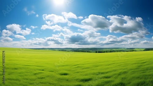 Beautiful natural scenic panorama green field of cut grass into and blue sky with clouds on horizon. Perfect green lawn on summer sunny day.