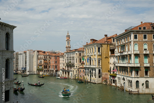 View of a river in Venice, featuring several boats of different sizes and colors, sailing in water © Wirestock