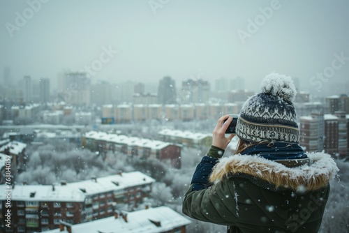 person in beanie taking pictures of snowy cityscape