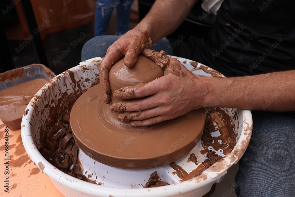 Person working on pottery in a clay bowl