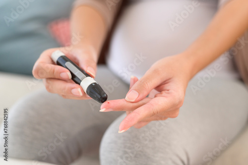 Pregnant woman checking blood sugar level by using Digital Glucose meter, health care, medicine, diabetes, glycemia concept