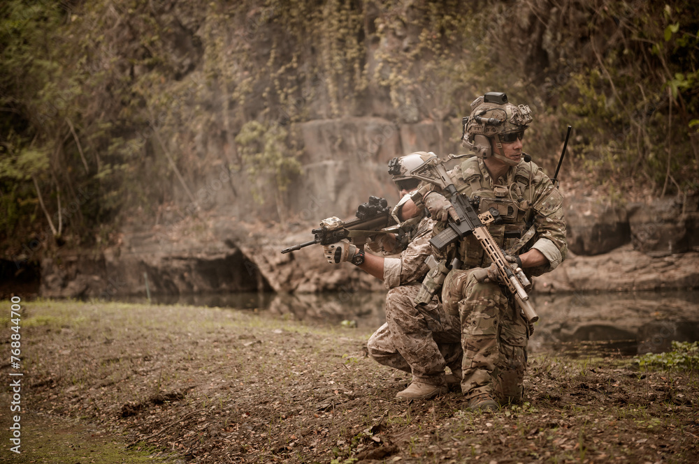 Soldiers in camouflage uniforms aiming with their rifles.ready to fire during Military Operation in the forest , soldiers training in a military operation Soldiers in camouflage uniforms aiming with their rifles.ready to fire during Military Operation in the forest , soldiers training in a military operation