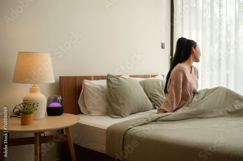 Young asian woman stretching in bed after Waking up in the Morning