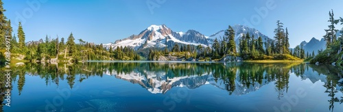 panoramic view of Mount Shuksan and snow capped peak reflecting in the clear blue water lake surrounded by pine trees © K'kriang Krai