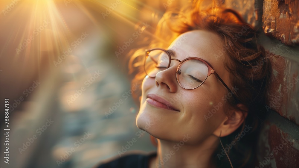 Woman basking in sunlight against a brick wall, eyes closed Woman basking in sunlight against a brick wall, eyes closed