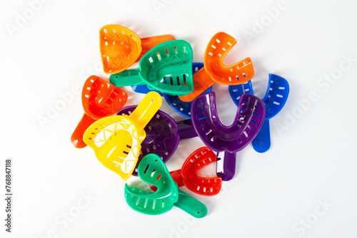 Multi-colored dental spoons for taking an impression of the dental jaw on a white background. Orthodontics in dentistry. photo