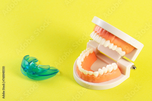 Therapeutic mouthguard on the background of a dental jaw mockup on a yellow background. Treatment of teeth grinding, bruxism in children and adults. Protecting tooth enamel 