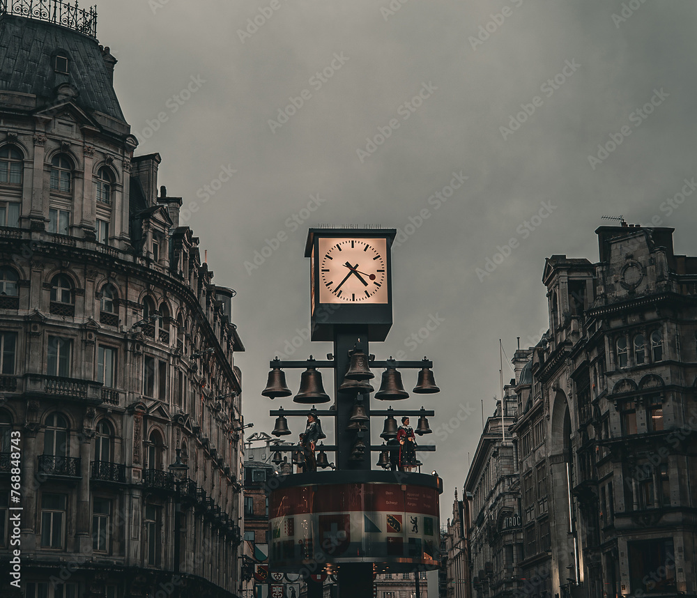 Obraz premium Clock outdoors in the city center of Leicester Square, London, dramatic colors, cloudy weather, evening