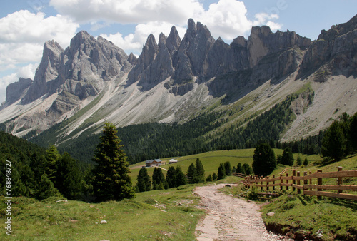 Panoramic view of a mountain range with wooden fence in the foreground in the Puez Odle-Geisleralm National Park in the Val Gardena region in Dolomites, South Tyrol, Italy photo