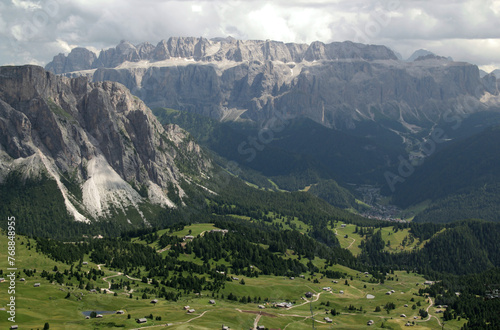 Landscape photo with a panoramic view of mountains and meadows with trees against a cloudy stormy sky in Dolomites, South Tyrol region, Italy