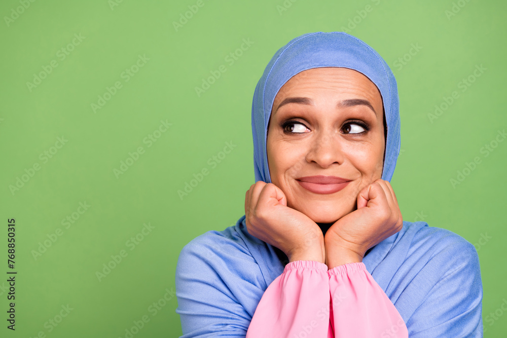 Photo of attractive arab girl wondered look empty space minded idea arms touch cheeks isolated over green color background Photo of attractive arab girl wondered look empty space minded idea arms touch cheeks isolated over green color background